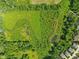 Stunning aerial view of green property featuring both open fields and tree cover, complete with a tranquil pond at 9656 Summerton Dr, Fishers, IN 46037