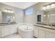 Bright bathroom showcases a soaking tub, white cabinetry, and large mirrors at 9656 Summerton Dr, Fishers, IN 46037
