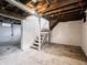 Unfinished basement with exposed ductwork, wooden staircase, and painted walls provides storage and potential for renovation at 1065 36Th St, Indianapolis, IN 46208