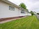 Well-maintained exterior featuring white siding, green trim, and a lush green lawn with chain-link fence at 1065 36Th St, Indianapolis, IN 46208