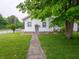 A cozy home with white siding, green trim, and a walkway leading to the front door at 1065 36Th St, Indianapolis, IN 46208
