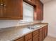 Galley kitchen featuring wood cabinets, double sink, stainless steel fixtures, and tile backsplash at 1065 36Th St, Indianapolis, IN 46208
