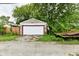 Garage with a white door, offering parking or storage, set against a backdrop of mature trees at 1106 W 4Th St, Anderson, IN 46016
