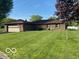Charming brick ranch home with well-maintained lawn, attached two car garage and mature trees under a bright blue sky at 1425 Winding Trail Cir, Greenwood, IN 46142