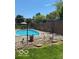 Backyard pool area surrounded by chain link fence and decorative rock, with shaded seating and patio at 1425 Winding Trail Cir, Greenwood, IN 46142
