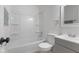 Clean bathroom features a white tub/shower combo, toilet, and a vanity with modern fixtures and storage at 1606 Asbury St, Indianapolis, IN 46203