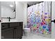 Bathroom featuring gray cabinets, sleek faucet, and a colorful shower curtain at 17359 Wilkes Way, Westfield, IN 46074