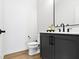 Modern powder room featuring a dark vanity with a black faucet, a white countertop, and a sleek mirror at 17359 Wilkes Way, Westfield, IN 46074