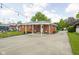 Backyard exterior showcasing a brick home, covered porch, and a concrete patio at 2110 Allison Ave, Speedway, IN 46224