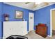 Bedroom with bright blue walls, ceiling fan, and white murphy bed and vintage dresser at 2623 Senators Way, Indianapolis, IN 46217
