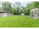 Expansive backyard with lush green lawn, greenhouse, storage shed, and a fire pit, perfect for outdoor activities at 305 W Vinyard St, Anderson, IN 46011