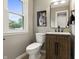 Stylized powder room features a wood vanity with dark fixtures and a tiger art piece at 3526 Westfield Dr, Anderson, IN 46011