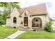 Charming stone house with covered porch and arched window, surrounded by lush greenery and a well-maintained lawn at 4435 E 38Th St, Indianapolis, IN 46218