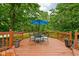 Wooden deck with outdoor dining set, surrounded by green trees and blue skies at 5412 Green Hills Dr, Brownsburg, IN 46112