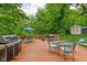 Spacious wooden deck with outdoor dining set, grill, and lush greenery, perfect for entertaining at 5412 Green Hills Dr, Brownsburg, IN 46112