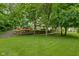 Manicured backyard with a wooden deck, terraced landscaping, and lush green lawn at 5412 Green Hills Dr, Brownsburg, IN 46112