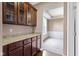 A butlers pantry with stained wood cabinetry and granite counters adjoins a room with white trim and large windows at 543 Amersham Ct, Avon, IN 46123