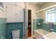 This bathroom features blue tile, a glass enclosed shower/tub combination, and white storage cabinets at 5616 Winthrop Ave, Indianapolis, IN 46220