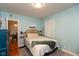 Cozy bedroom with a decorative wicker headboard, light blue walls, hardwood floors and attached full bathroom at 5616 Winthrop Ave, Indianapolis, IN 46220