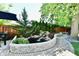 Landscaped backyard with a serene stone-lined pond, waterfall feature, lush greenery, and a charming brick patio at 6187 Crittenden Ave, Indianapolis, IN 46220