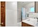 Bathroom featuring a white tiled shower and sink, plus wood cabinets at 6430 E Southport Rd, Indianapolis, IN 46237
