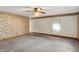 Spacious bedroom featuring neutral carpet, ceiling fan, and floral wallpaper accents at 6430 E Southport Rd, Indianapolis, IN 46237