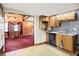 Charming kitchen view into living area, featuring wood cabinets and a stainless steel dishwasher at 6430 E Southport Rd, Indianapolis, IN 46237