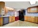 Functional kitchen with light wood cabinets, stainless steel dishwasher, and vintage wallpaper at 6430 E Southport Rd, Indianapolis, IN 46237
