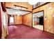 Large living room showcasing wood paneling, neutral carpet, and an open floor plan to the kitchen at 6430 E Southport Rd, Indianapolis, IN 46237