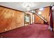 Open living room featuring a chandelier, wood paneled walls, and access to the kitchen at 6430 E Southport Rd, Indianapolis, IN 46237