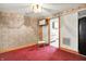 Cozy living room featuring patterned wallpaper, red carpet, and a doorway leading to the kitchen at 6430 E Southport Rd, Indianapolis, IN 46237