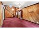 Spacious living room featuring wood paneling, a decorative chandelier, and staircase at 6430 E Southport Rd, Indianapolis, IN 46237