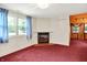 Living room with a fireplace, built-in shelves, red carpet, and blue curtains at 6430 E Southport Rd, Indianapolis, IN 46237