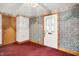Inviting living room featuring a floral wallpaper accent wall, white trim, and a glass-paneled entry door at 6430 E Southport Rd, Indianapolis, IN 46237