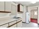 The utility room features white cabinets, a sink, a hot water heater, and a door to another room at 6430 E Southport Rd, Indianapolis, IN 46237