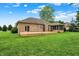 A large green backyard featuring a brick home with a screened porch and a wooden deck at 7310 Monaghan Ln, Indianapolis, IN 46217
