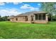 A well-manicured backyard featuring a brick house, deck, screened porch, and lush green lawn at 7310 Monaghan Ln, Indianapolis, IN 46217