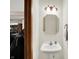 Small bathroom with pedestal sink and octagon mirror; view into room beyond at 7310 Monaghan Ln, Indianapolis, IN 46217