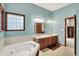 Bathroom features tile floor, blue walls, built-in tub, and dual-sink vanity at 7310 Monaghan Ln, Indianapolis, IN 46217