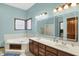 Bathroom features a bathtub, tile floors, blue walls, a vanity with double sinks, and a large mirror at 7310 Monaghan Ln, Indianapolis, IN 46217