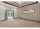 A bedroom features beige walls, carpet, French doors, and a window with a view of the lush backyard at 7310 Monaghan Ln, Indianapolis, IN 46217