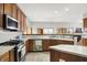 Kitchen featuring stainless appliances, wood cabinets, and modern fixtures, and partially open to the dining room at 7310 Monaghan Ln, Indianapolis, IN 46217