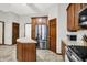 A kitchen features a stainless steel refrigerator, tile floors, wooden cabinetry, and an island with a white countertop at 7310 Monaghan Ln, Indianapolis, IN 46217