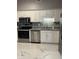 Modern kitchen with stainless steel appliances, white cabinets, granite counters, and a tile backsplash at 7601 Newport Bay Dr # 203, Indianapolis, IN 46240