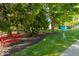 Relaxing community green space with mature trees, a bright red bench, and a little blue library at 7650 Micawber Ct, Indianapolis, IN 46256