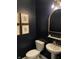 Stylish powder room featuring dark walls, decorative mirror and sconce lighting, and modern fixtures at 8876 Boylan Pl, Pendleton, IN 46064