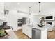 Bright, white kitchen with stainless appliances, island with barstool seating, and seamless flow to the living room at 9351 Abner St, McCordsville, IN 46055