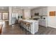 Modern kitchen boasts stainless steel appliances, grey cabinets, hardwood floor, and a spacious center island with bar stool seating at 9387 Abner St, McCordsville, IN 46055