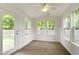 Bright sunroom featuring wood floors, multiple windows, and a ceiling fan, with door access to outdoors at 975 Atir Ln, Greenfield, IN 46140
