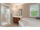 Well-lit bathroom featuring a glass shower, vanity, and tub with natural light at 10501 Greenway Dr, Fishers, IN 46037